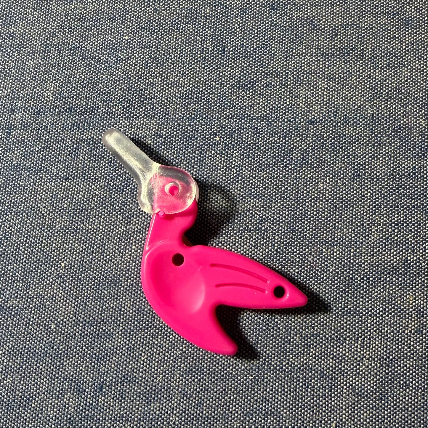 Pink bird-shaped needle-threader on a gray background