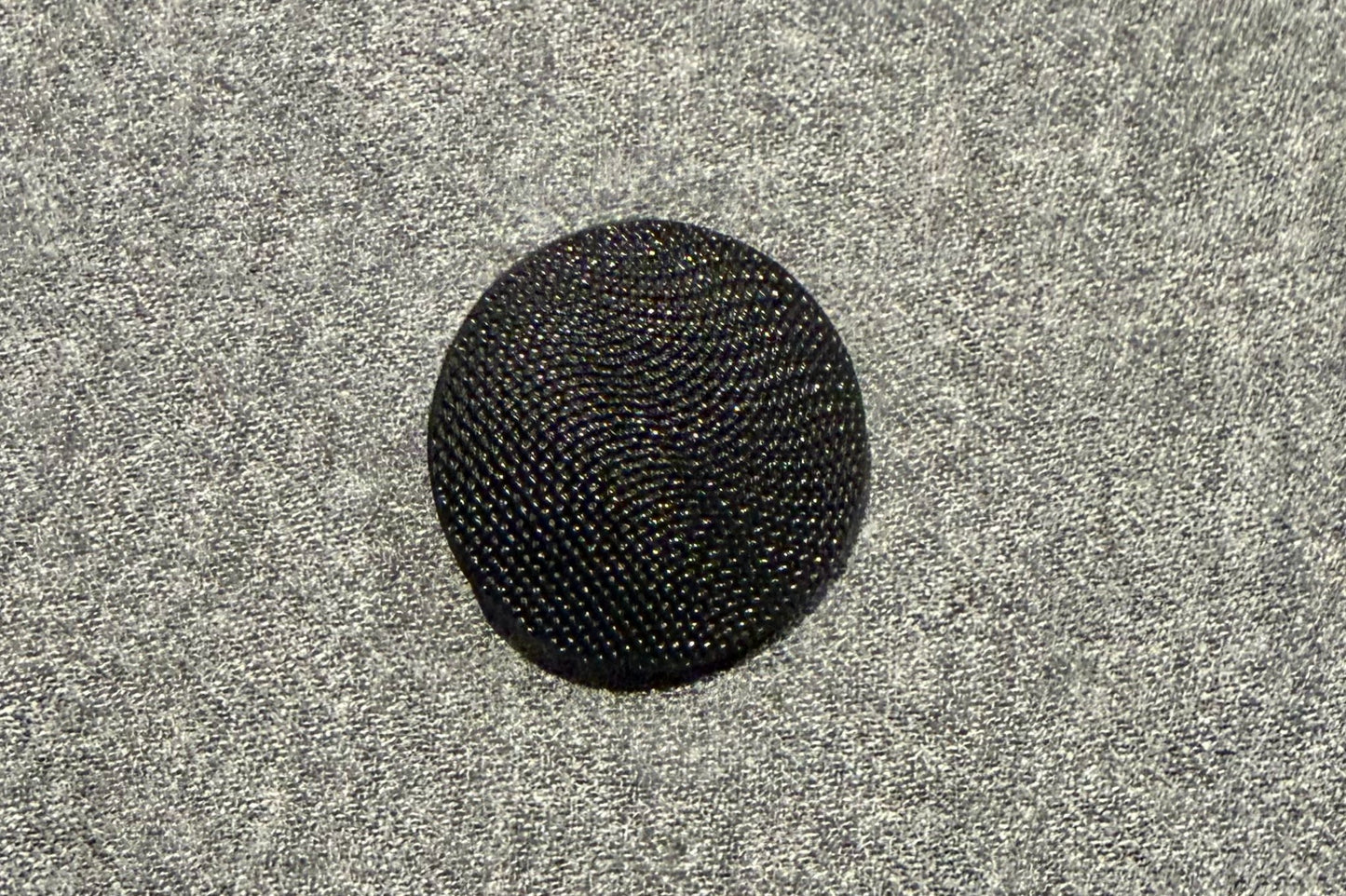 Black textured button on a gray textured background