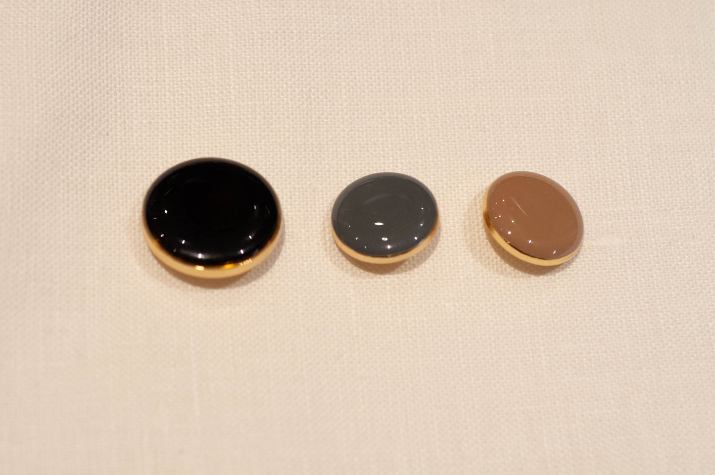 Three round buttons with different colors on a beige fabric background
