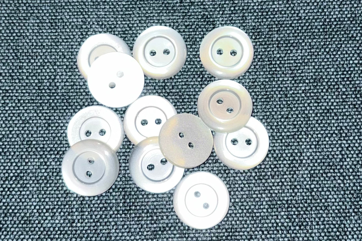 White buttons scattered on a textured gray fabric background