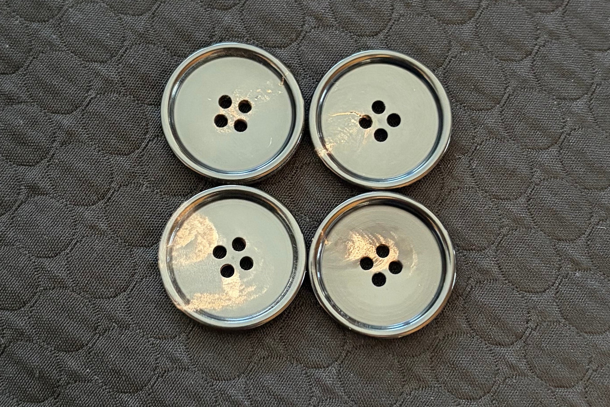 Set of polished black buttons on a textured black surface