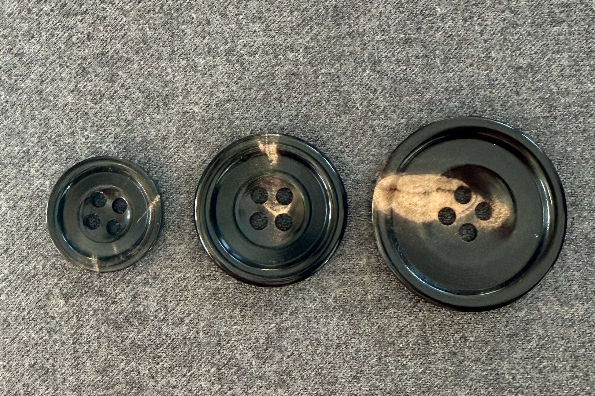 Three black buttons of different sizes on a gray surface