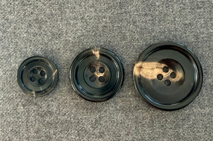 Three black buttons of different sizes on a gray surface