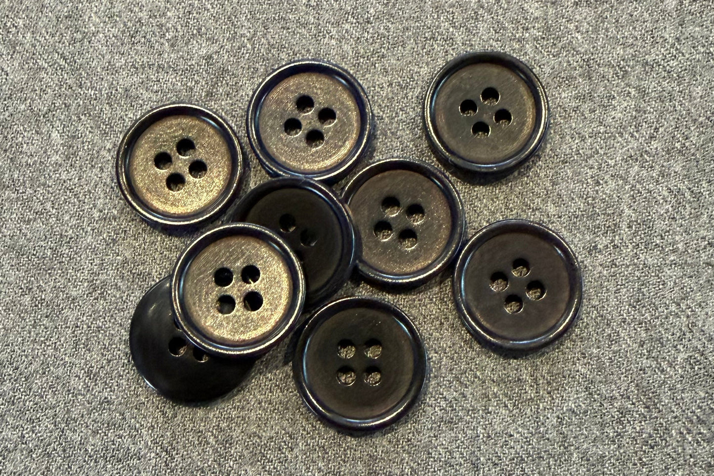 Group of black buttons on grey fabric