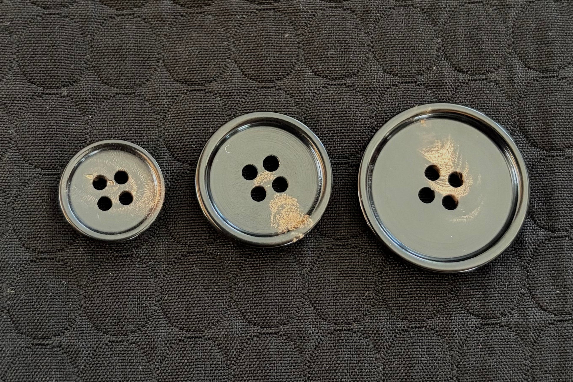 Three polished black buttons on a textured gray surface