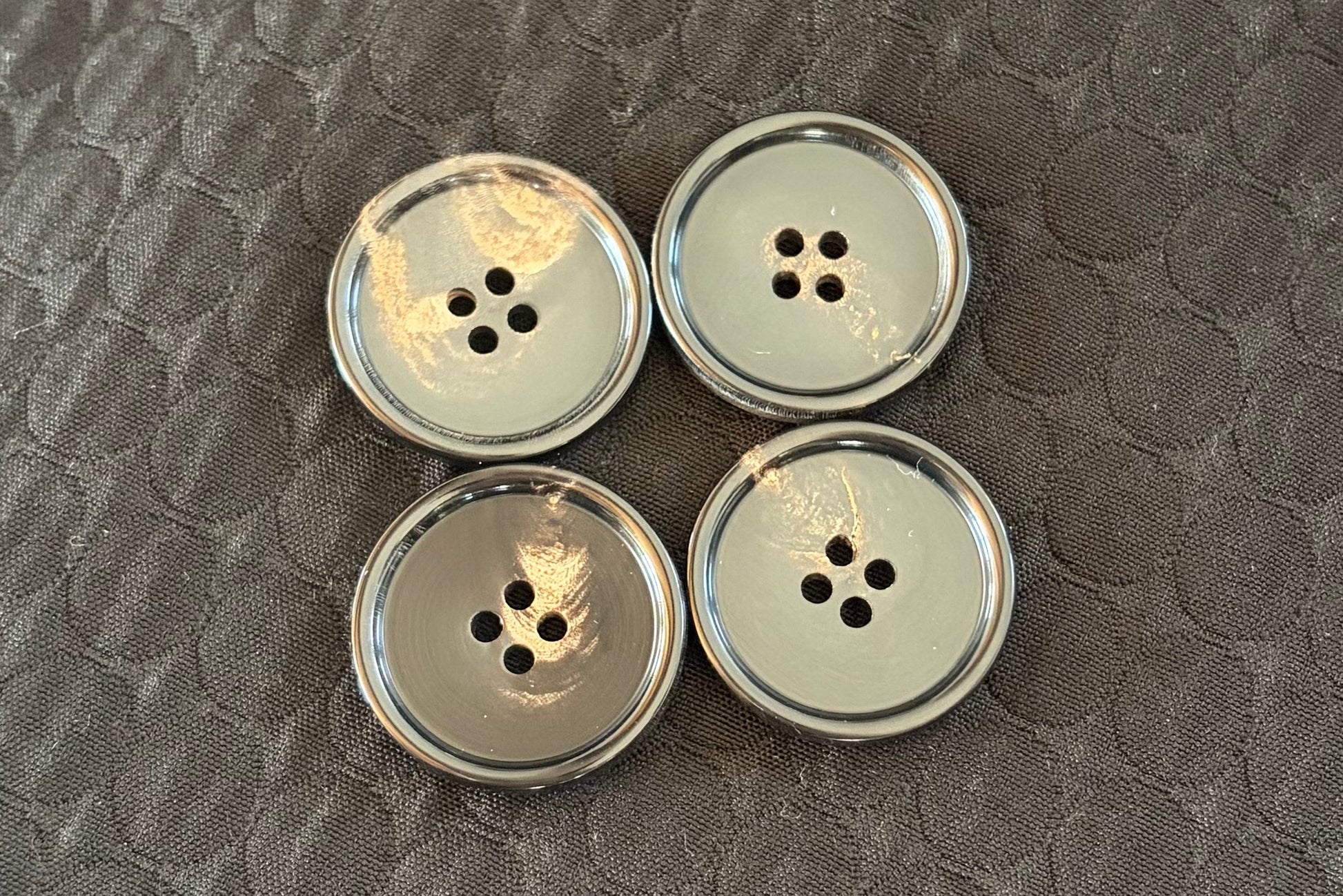 Four black polished buttons on a textured dark surface