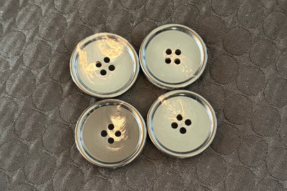 Four black polished buttons on a textured dark surface