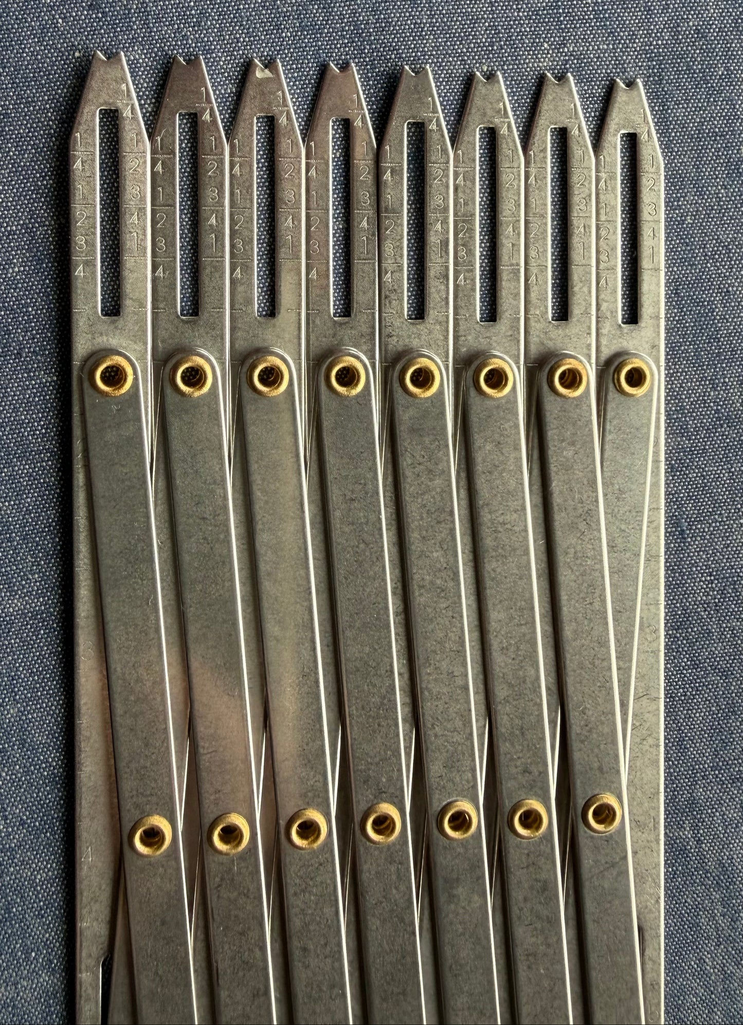 Accordion-like sewing gauge with measurement markings on blue fabric.