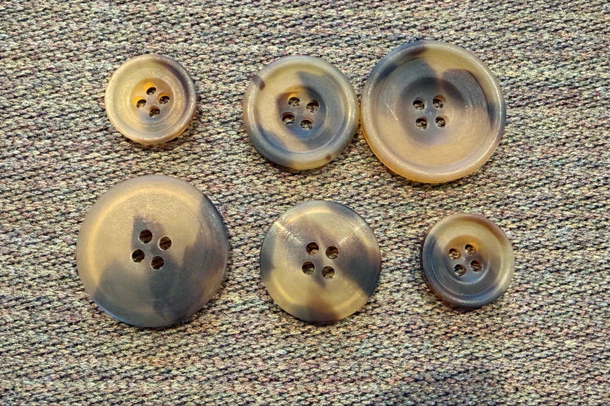 Set of six brown buttons on a textured gray surface