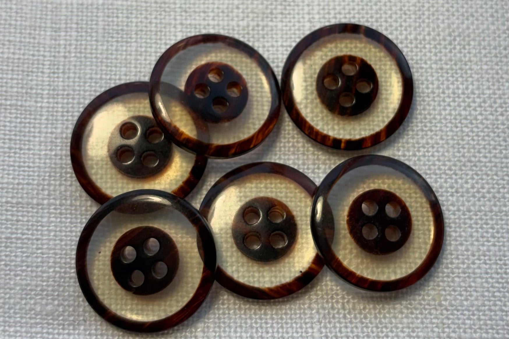 Set of six clear and brown buttons  on a white fabric background