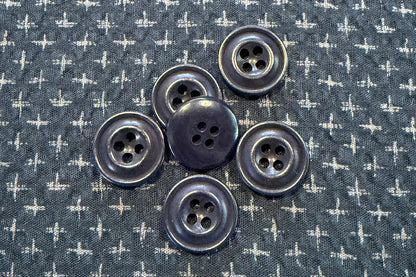 Blue buttons on a blue fabric background with white cross patterns