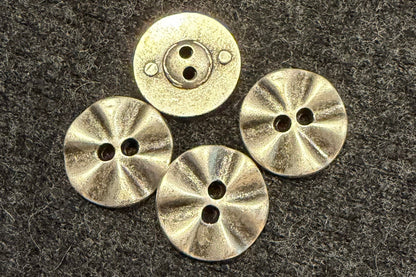 Four metal buttons on a textured dark fabric background