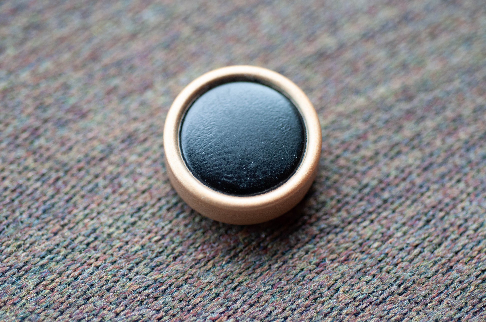 Round black object with a gold rim on a textured surface