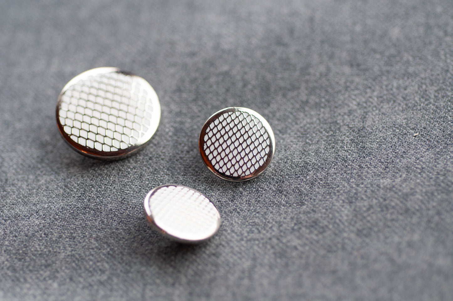 Three metallic buttons with textured surfaces on a gray background