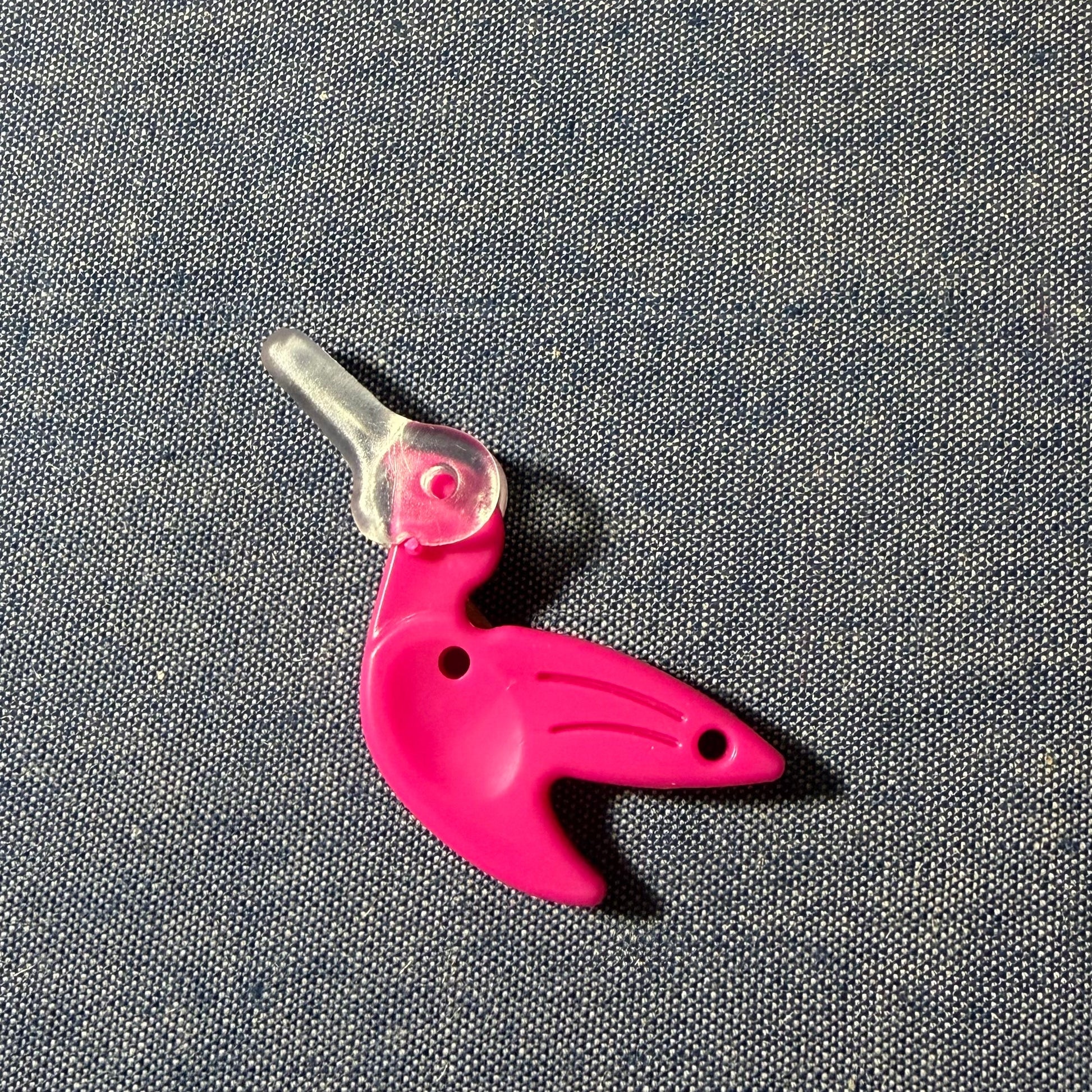Pink bird-shaped needle-threader on a gray background