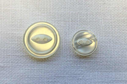 Two small round buttons on a textured fabric background