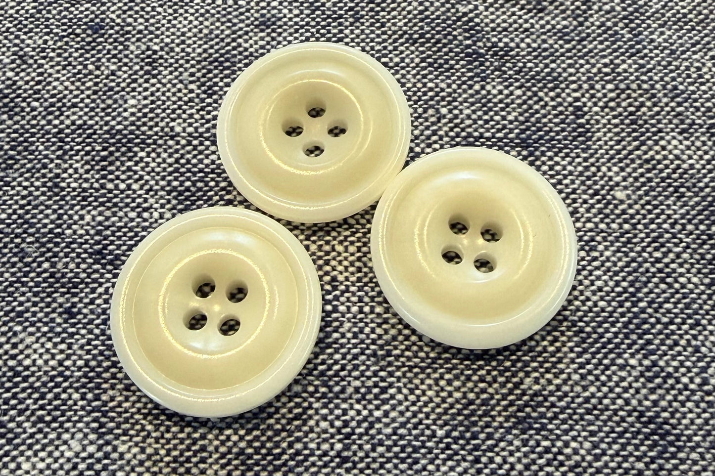 Three white buttons on a textured gray fabric background