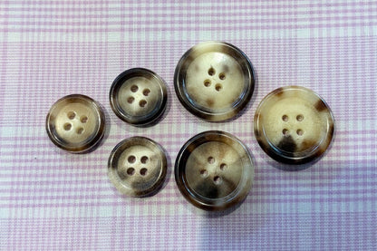 Set of six cream and brown buttons on a textured fabric background