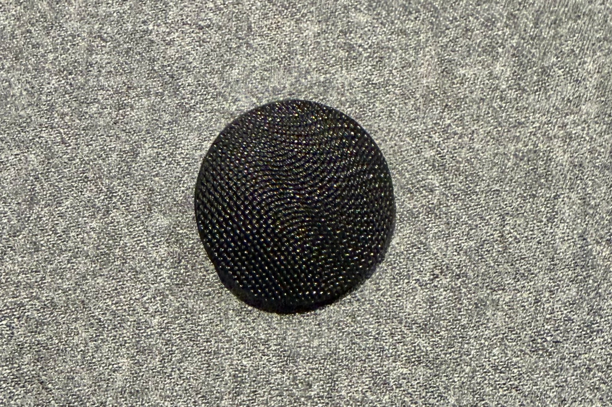 Black textured button on a gray textured background