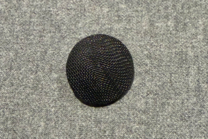 Black textured button on a gray textured background