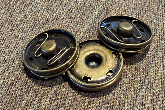 Three metallic snaps on a textured fabric surface