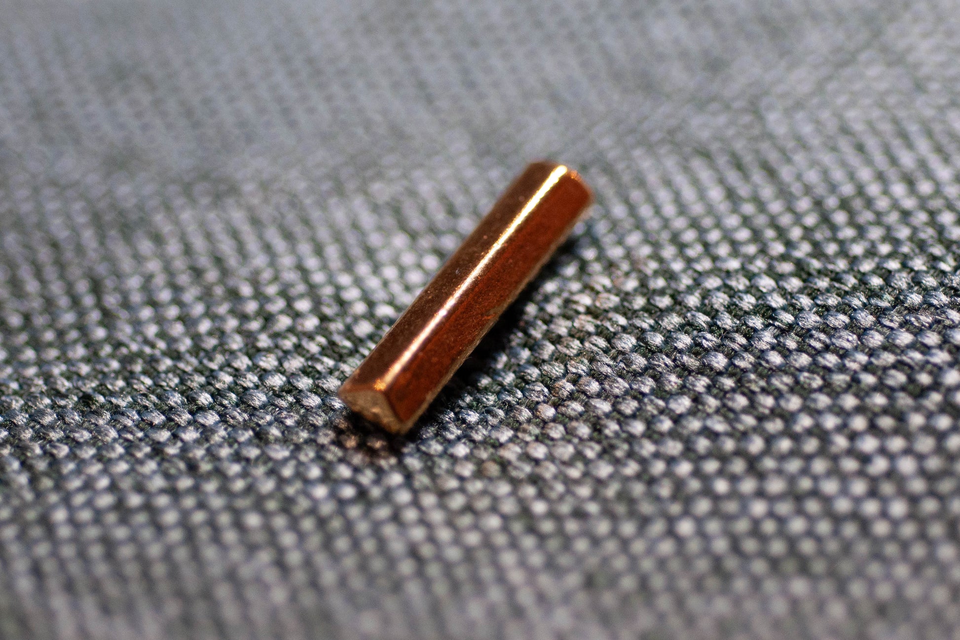 Bronze cylindrical button on a textured gray fabric background
